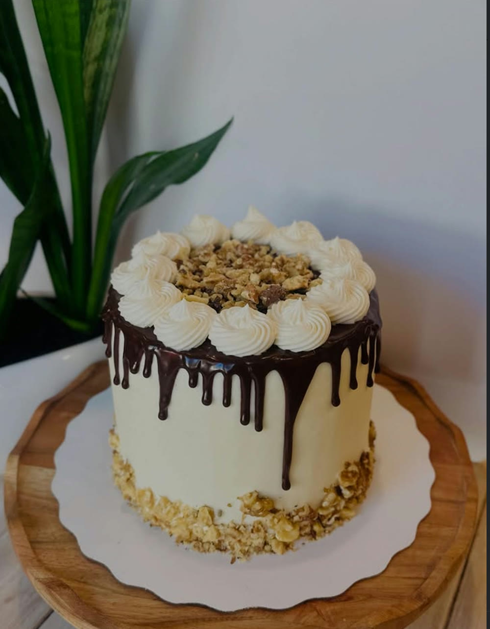 A buttercream layer cake with chocolate drip and toasted walnuts