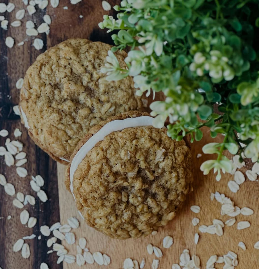 Two oatmeal cream sandwich cookies on a wooden board